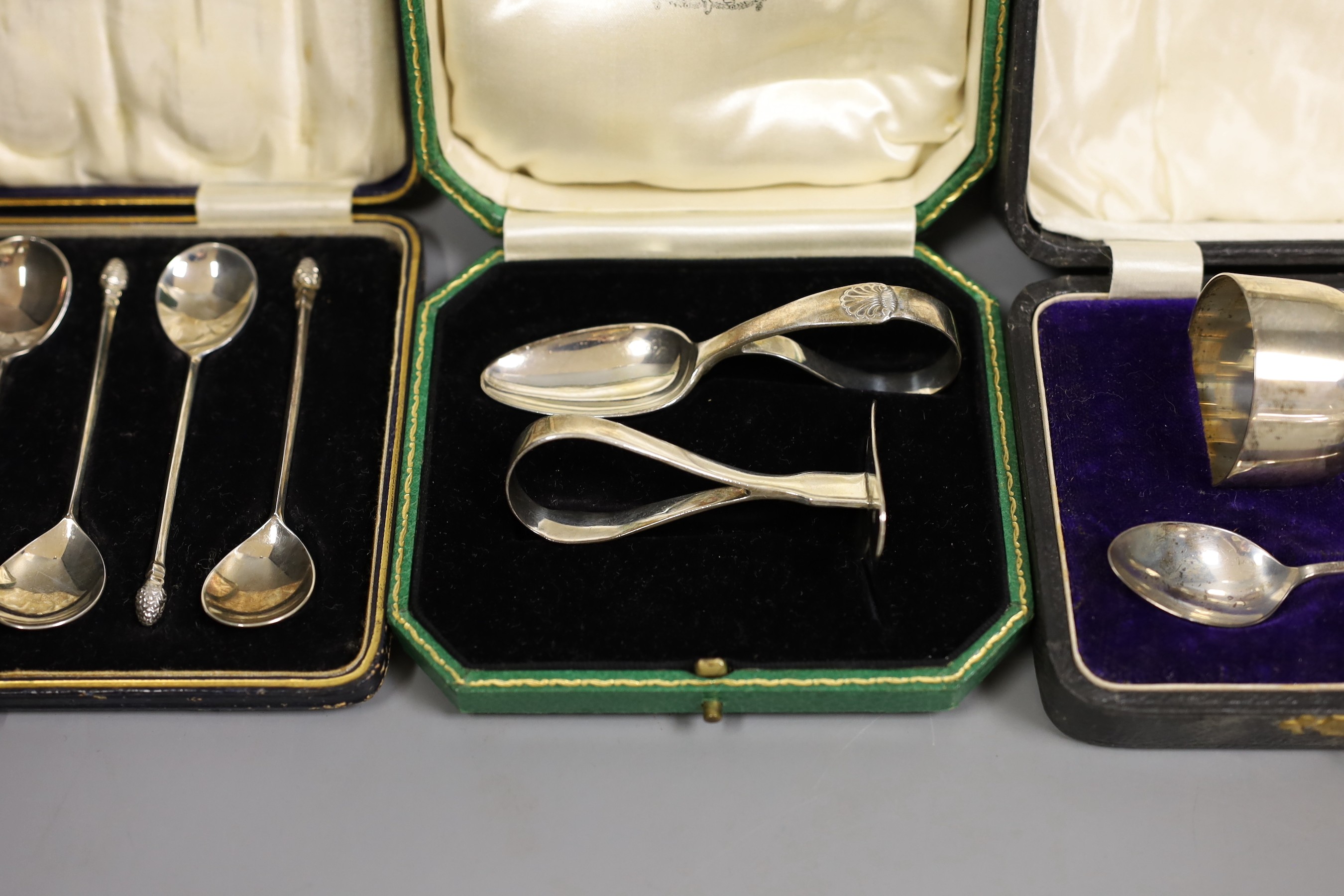 Two cased silver Christening sets, egg cup and spoon and pusher and spoon, a cased set of acanthus terminal coffee spoons, and a cased set of six apostle teaspoons and tongs, 7oz.